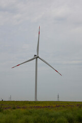 Industrial wind turbines are on the plain. Huge windmills stand on the plain under a gloomy sky.