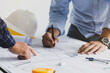 © Pcess609 - engineer meeting for an architectural project. working with partner and engineering tools working on blueprint architectural project at the construction site at desk in the office.