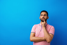 Pensive Young Arab Man Thinking And Looking Up Against Blue Background