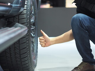 Man hand thumb up near big wheel of new car