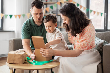 Wall Mural - family, holidays and people concept - happy mother, father and little son opening birthday presents at home party