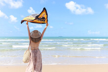 Beautiful Asian Woman With Hat From Behind Holding A Shawl And Raising It Up, Enjoy Spending Time  On Tropical Sand Beach Blue Sea, Resting And Relaxing On Summer Holiday Vacation.