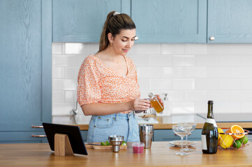 culinary and people concept - happy smiling young woman with tablet pc computer making cocktail drinks at home kitchen