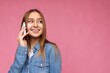 © Ivan Traimak - Closeup Photo of Attractive positive smiling young blonde woman wearing casual blue jean shirt isolated over pink background holding in hand and talking on mobile phone looking to the side