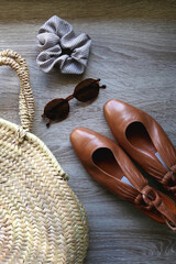 Wall Mural - Straw bag, vintage shoes, sunglasses and scrunchie on wooden background. Flat lay.