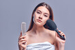 © Olena Apetroaiei - Portrait of a beautiful attractive cute well-groomed lady holding a comb in her hand, smooth, soft, silky hair, keratin effect, isolated on gray background.