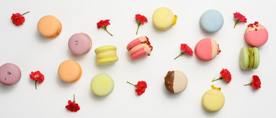 Wall Mural - baked macarons with different flavors and rosebuds on a white background