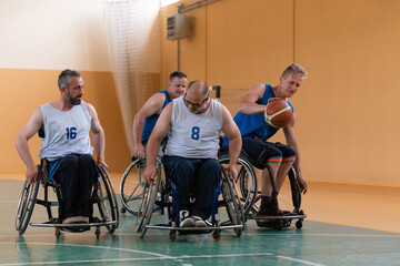 Disabled War veterans mixed race opposing basketball teams in wheelchairs photographed in action while playing an important match in a modern hall. 