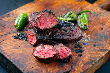 Wall Mural - Traditional barbecue wagyu onglet steak with green chili and spices served as close-up on a rustic wooden board
