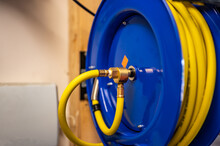 Auto-rewinding Air Hose Reel With Coiled Tubing Mounted On A Wall In A Shop