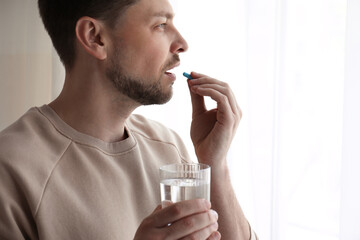 Wall Mural - Man with glass of water taking pill at home