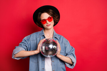 Photo portrait girl smiling wearing hat sunglass keeping discoball isolated vivid red color background