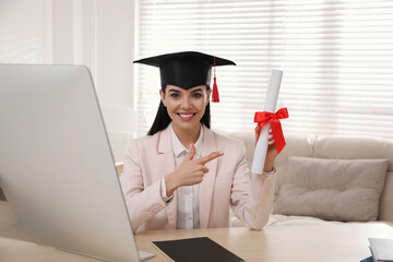 Wall Mural - Happy student with graduation hat and diploma at workplace in office