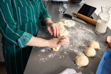 Wall Mural - Close up of female baker hands kneading dough.