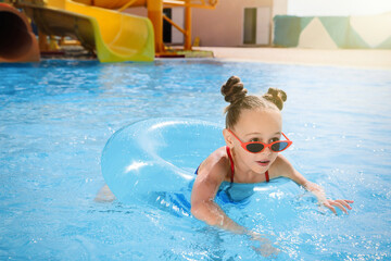 Poster - Cute little girl with inflatable ring in swimming pool at water park