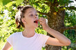 © IULIIA GUSEVA - in summer garden young cute girl in white T-shirt holds ripe cherry berry in her mouth. Delicious and healthy food. Close-up