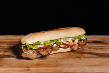 Small Meat And Vegetable Sandwich On A Wooden Table With A Black Background
