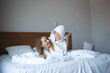 © Aleksandra Iarosh - mom and daughter lie on the bed in white hotel robes after a shower