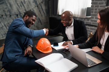 Wall Mural - African American businessmen sit at the table and shake hands in honor of the conclusion of the deal