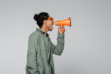 side view of stylish african american man screaming in megaphone isolated on grey