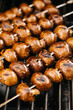 Rows of Cremini mushroom skewers on the grill