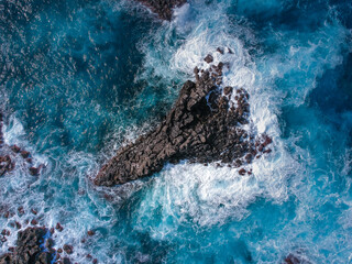 Sticker - Aerial top view of sea waves hitting black volcanic rocks