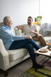© Cavan Images - Elderly and young men chatting on settee
