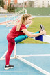 © Cavan Images - Female runner with prosthesis stretching legs at stadium