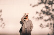 © Cavan Images - Young woman shielding eyes standing against wall in city