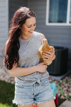 Woman Holds Chicken In Her Backyard On A Sunny Day