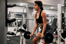 Young Woman Lifts Weights In A Gym