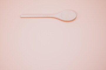 Sticker - Wooden spoon isolated on a peach background with free space for text