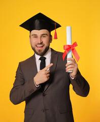 Wall Mural - Happy student with graduation hat and diploma on yellow background