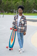Young african american girl skateboarder hold longboard in skate park. Modern urban female in casual street style clothes in city skatepark with skateboard training longboarding. Hipster hobby concept