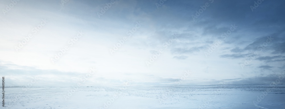 Panoramic view of the snow-covered field after a blizzard at sunset. Human tracks in a fresh snow. Ice desert. Dramatic cloudscape. Global warming theme. Lapland, Finland - obrazy, fototapety, plakaty 