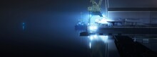 A Fishing Boat Moored To A Pier In A Fog At Night. Port Cranes In The Background. Yacht Club Illuminated By Lanterns. Reflections On The Water. Daugava River, Riga, Latvia