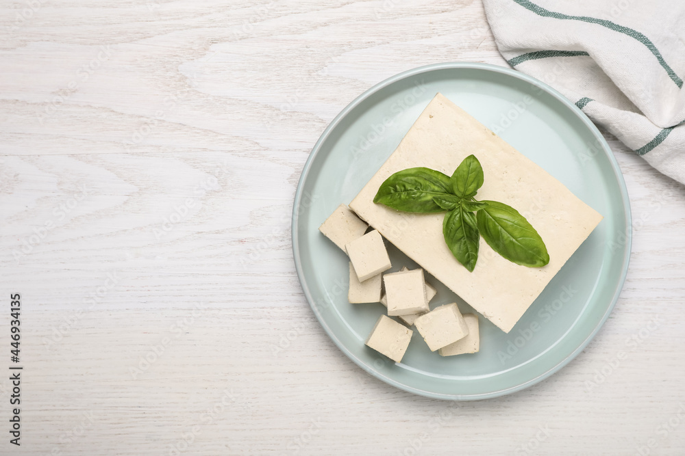 Delicious tofu with basil on white wooden table, top view. Space for text - obrazy, fototapety, plakaty 