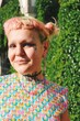 portrait of queer young woman with lgbtqia rainbow pride flag themed clothing and pink green hairstyle and tattos in pride parade