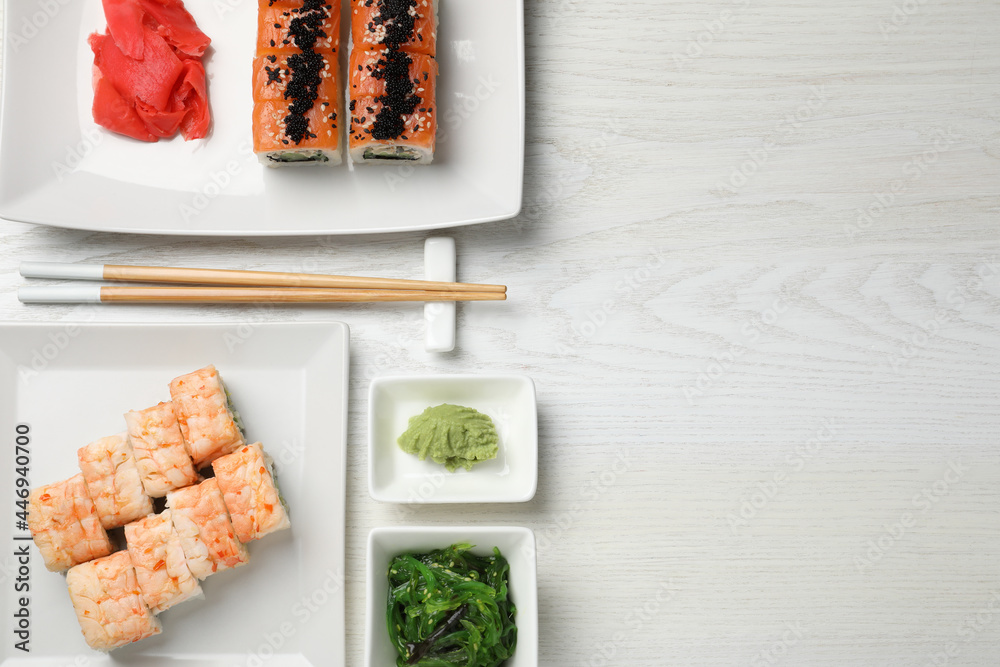 Delicious sushi rolls served on white wooden table, flat lay. Space for text - obrazy, fototapety, plakaty 