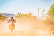 © Cavan Images - Man riding his adventure motorbike on dusty road in Cambodia
