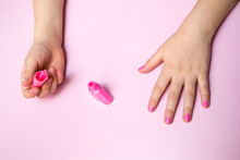 Girl's hands with a pink manicure.