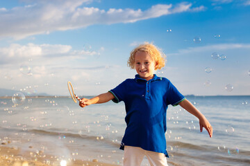 Wall Mural - Kids blow bubble at beach. Child with bubbles