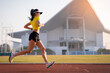 © EduLife Photos - A young Asian woman athlete runner jogging on running track in city stadium in the sunny morning to keep fitness and healthy lifestyle. Young fitness woman runs on stadium track. Sport and recreation