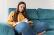© Damian - girl reading a book sitting on the sofa