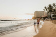 © Cavan Images - Father and daughter hold hands while they walk along beach at sunset