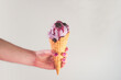 © Cavan Images - Hand holding berry ice cream in a waffle cone