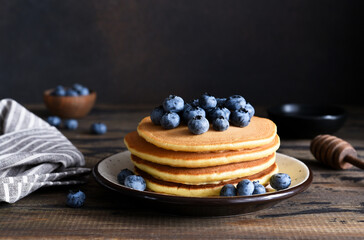 Canvas Print - Homemade pancakes on a wooden background with honey and blueberries.