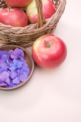 Wall Mural - Wicker basket of red apples and hydrangea petals isolated on a cream background