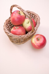 Poster - Vertical shot of red apples on a wicker basket isolated on a cream background with copy space