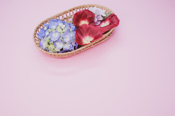 Poster - Fresh hydrangeas and Shirly poppy flowers on a wicker basket isolated on light pink background